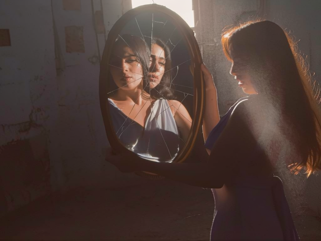 Mulher diante de espelho partido — metáfora da identidade fragmentada